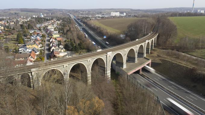 Luftaufnahme einer Eisenbahnbrücke, die über eine Autobahn führt. Es ist ein Bauwerk aus dem 19. Jahrhundert.