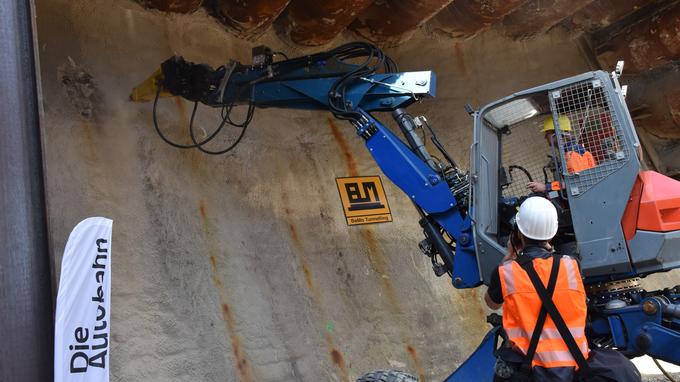 Ein Schreitbagger setzt mit einem Meißel an der betonierten Wand an, um den Vortrieb des Tunnels Baukau zu starten. 