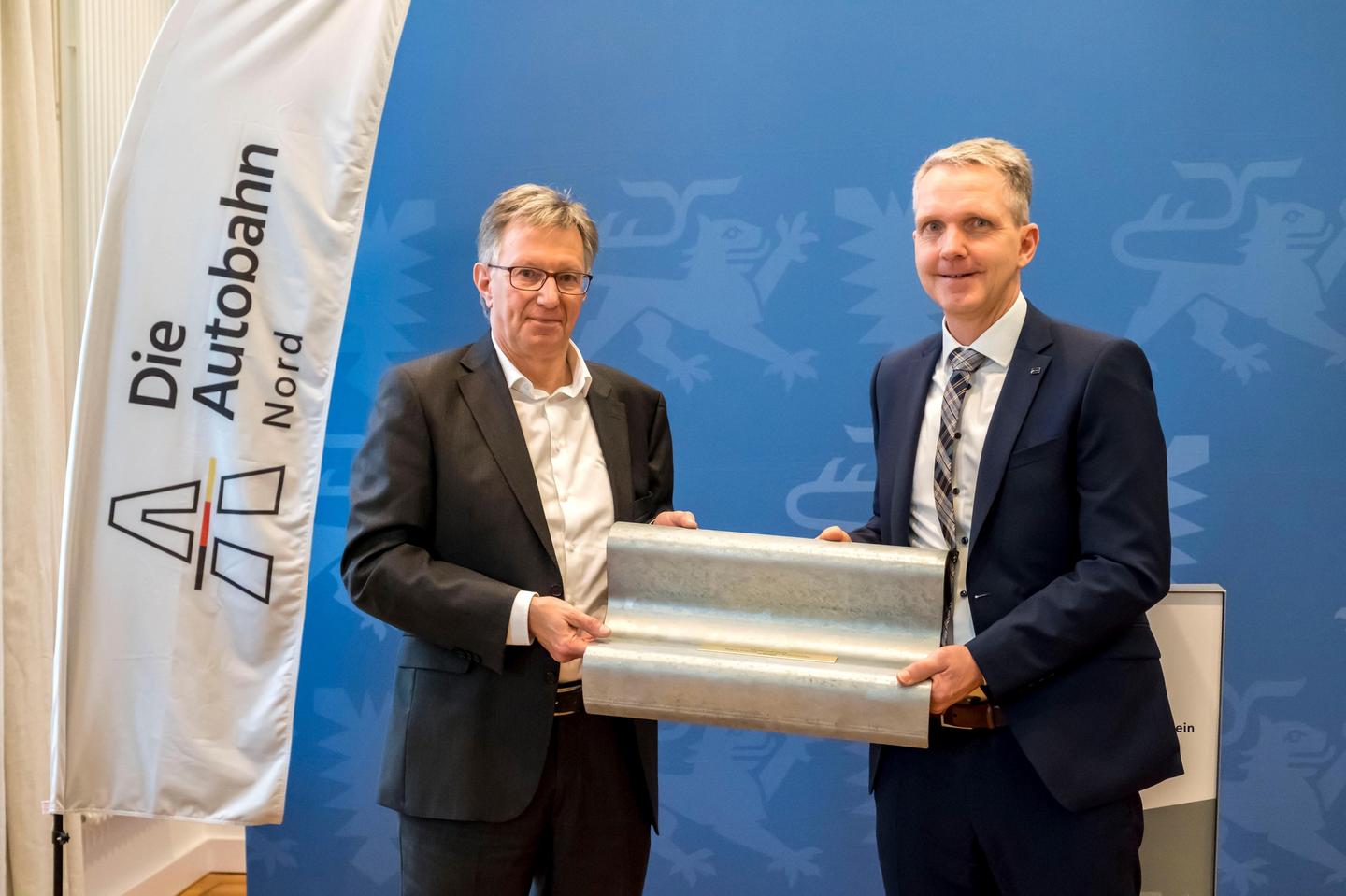 Klaus Franke übergibt ein Stück Leitplanke an den neuen Niederlassungsdirektor Carsten Butenschön.