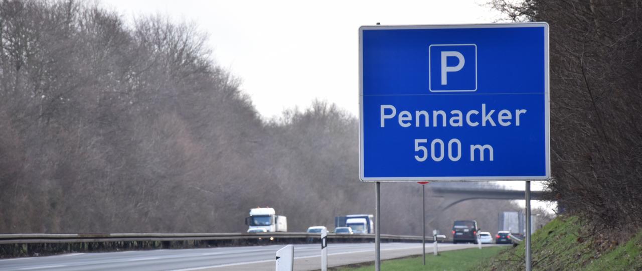 Das Bild zeigt eine blaue Hinweistafel an der Autobahn mit der Aufschrift "Pennacker 500 m"