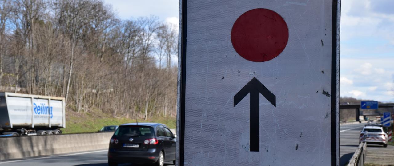 Ein Umleitungsschild mit einem Roten Punkt an der Autobahn.