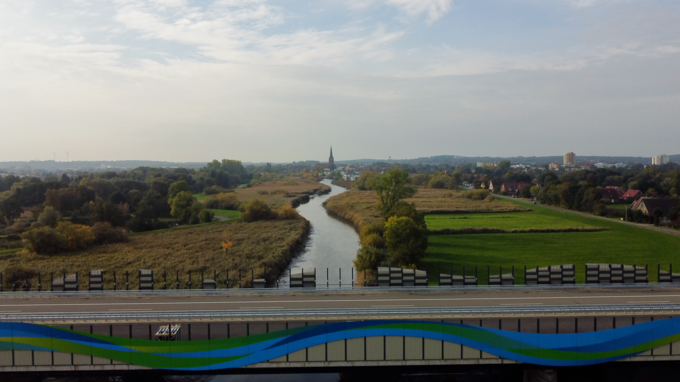 A26 Drohnen-Panoramaaufnahme von der Este Brücke aus Süden auf Buxtehude mit der Kirche. Im Vordergrund sieht man die bunte Lärmschutzwand der Brücke über die Este, die eine "Welle" darstellt.