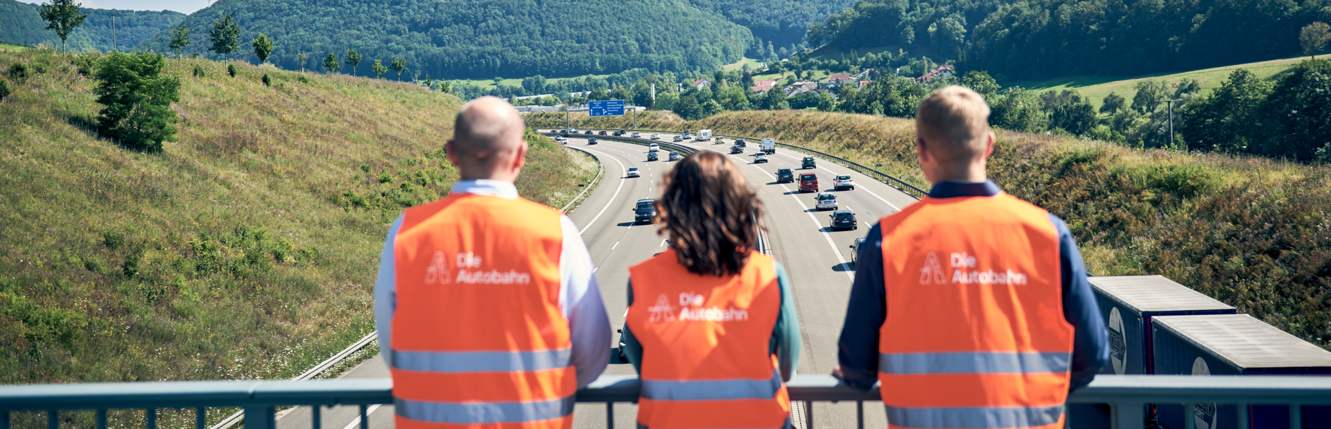 Drei Mitarbeitende der Autobahn GmbH stehen auf einer Autobahnbrücke