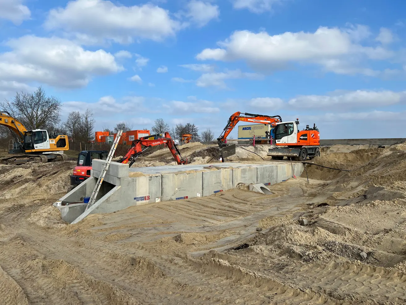 Mit drei Schaufelbaggern wird der Sand rund um den Durchlass eingebaut. © Die Autobahn GmbH des Bundes