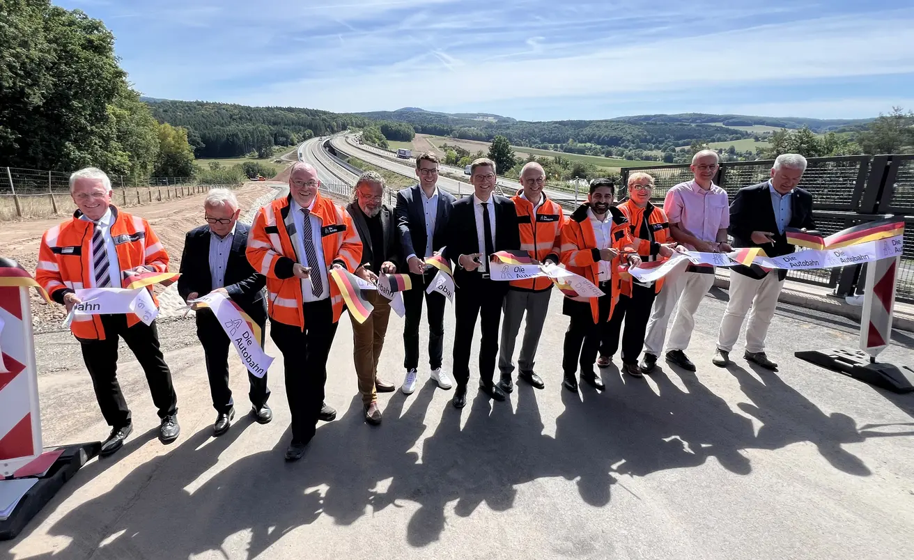 A7 Freigabe TBW Thalau Banddurchschnitt.jpg Banddurchschnitt für die Freigabe des ersten neuen Teilbauwerks mit Außerbetriebnahme des kompletten alten Bestandbauwerks. Von links nach rechts: Bernhard Klöpfel (Leiter der Außenstelle Kassel der Autobahn GmbH des Bundes), Willi Kropp (Firma Kropp Bau), Cord Lüesse (Direktor der Niederlassung Nordwest der Autobahn GmbH des Bundes), Johannes Rothmund (Bürgermeister der Gemeinde Eichenzell), Sebastian Müller (Mitglied des Hessischen Landtags), Christian Hirte (Parlamentarischer Staatssekretär beim Bundesminister für Verkehr), Dirk Brandenburger (Geschäftsführer Technik der Autobahn GmbH des Bundes), Kaweh Mansoori (Hessischer Minister für Wirtschaft, Energie, Verkehr, Wohnen und ländlichen Raum), Julia Rös (Leiterin der Außenstelle Fulda der Autobahn GmbH des Bundes), Michael Brand (Mitglied des Deutschen Bundestags) und Bernd Woide (Landrat des Landkreises Fulda).