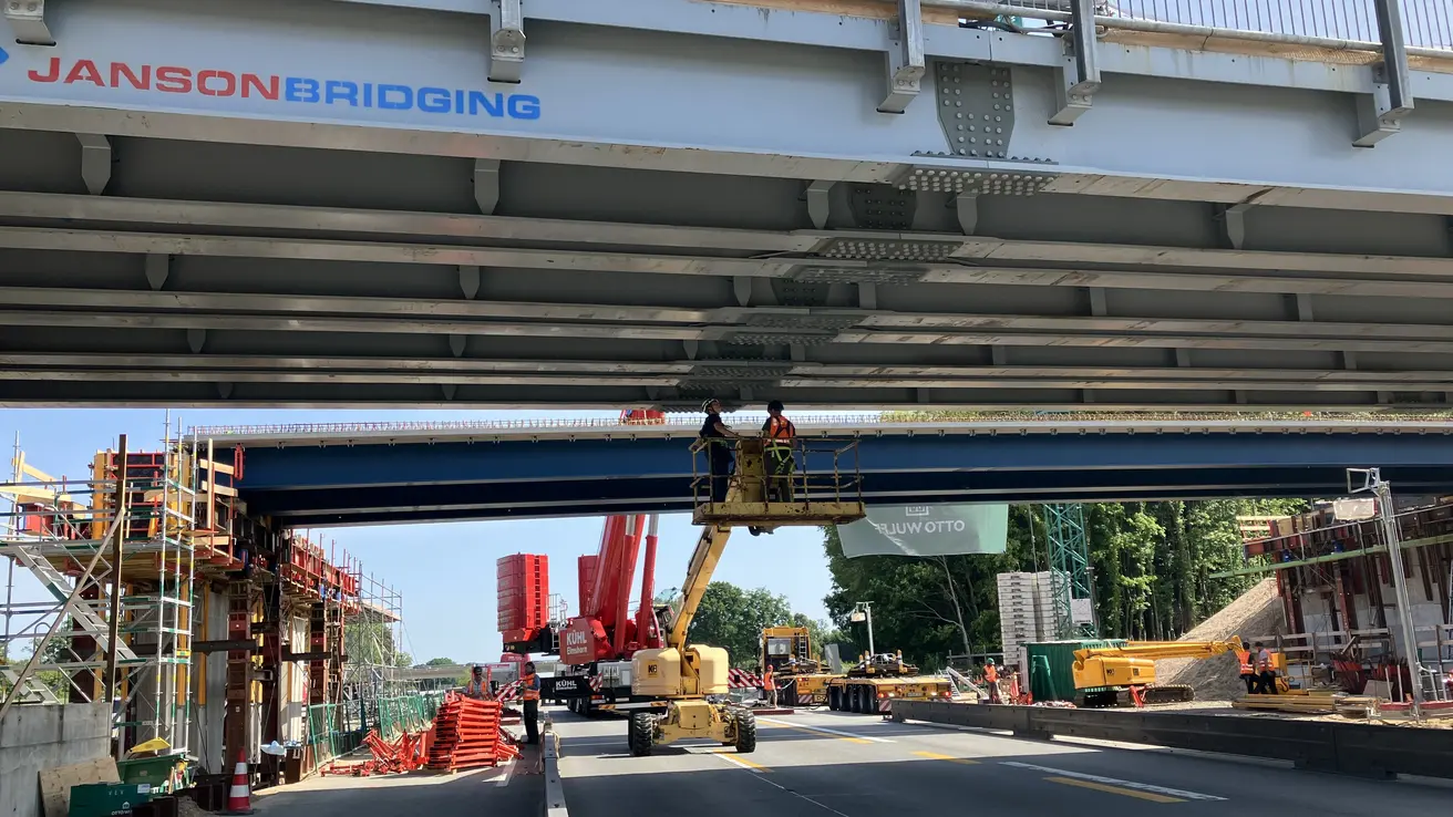 Während auf der einen Richtungsfahrbahn der Verkehr fließt, werden auf der anderen die Brückenträger bei bestem Wetter eingehoben.