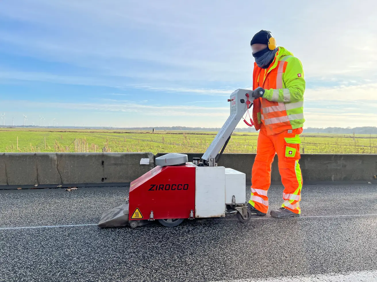 Das Trocknen der Fahrbahn mit 600 Grad heißer Luft aus diesem überdimensionalen Fön ist Handarbeit. Ohne die Trocknung würden Kleber und Markierung nicht ausreichend gut am Apshalt haften. © Die Autobahn GmbH des Bundes