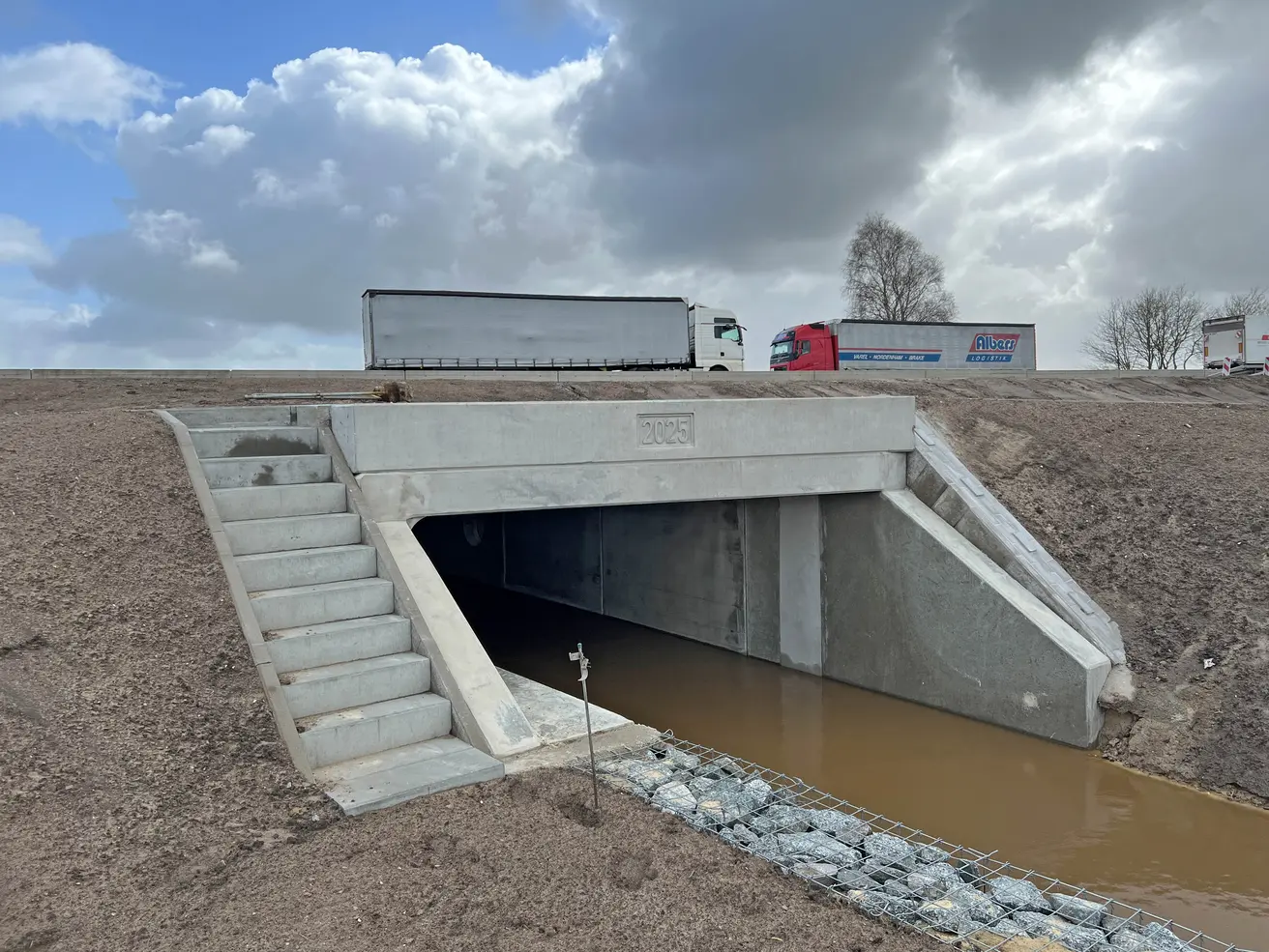 Die Westseite des Durchlasses. Im Vordergrund: eine mit Wassersteinen gefüllte Gabione, die verhindert, dass der Uferbereich unterspült wird. © Die Autobahn GmbH des Bundes