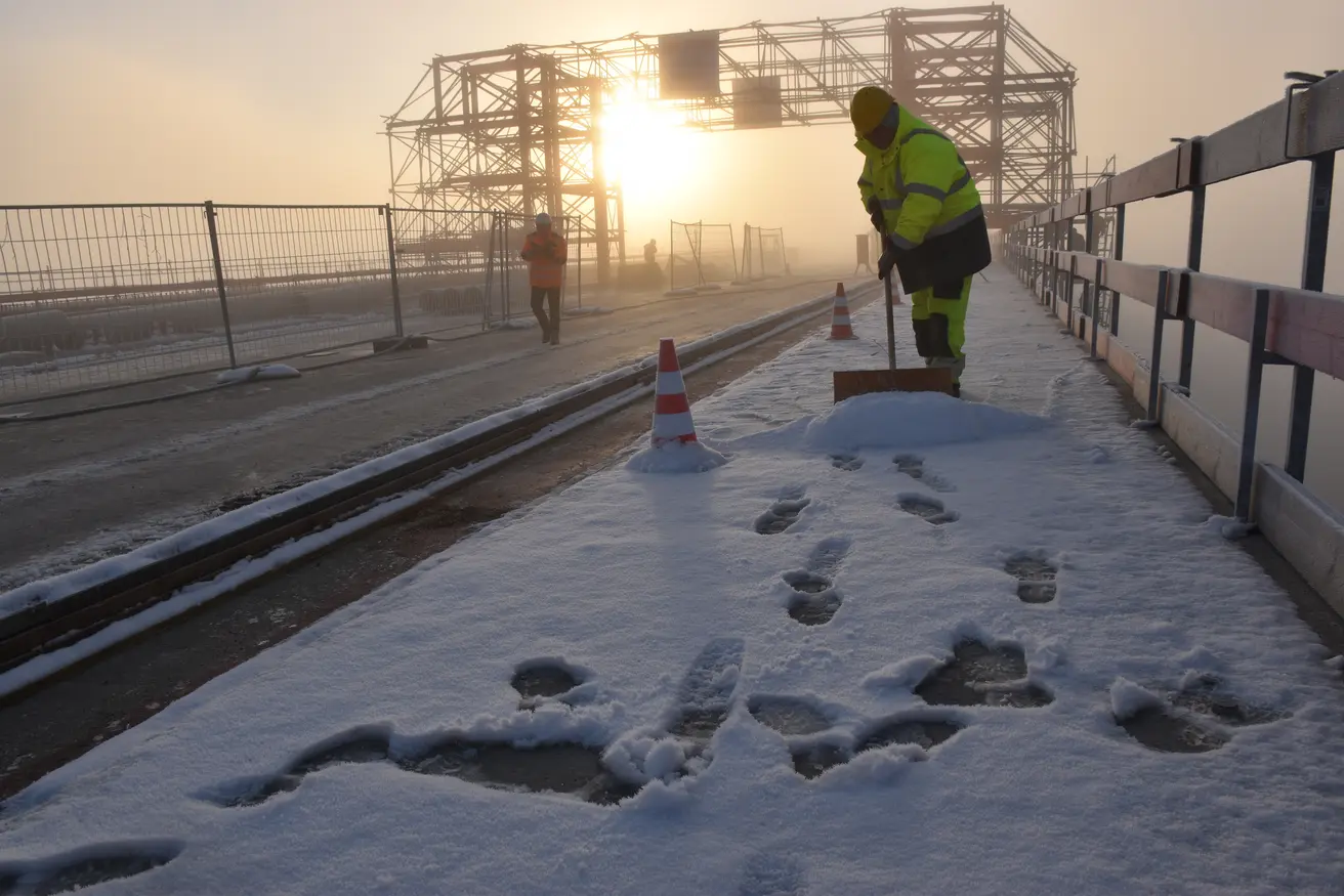 Ein Arbeiter schiebt auf der Baustelle Schnee beiseite.