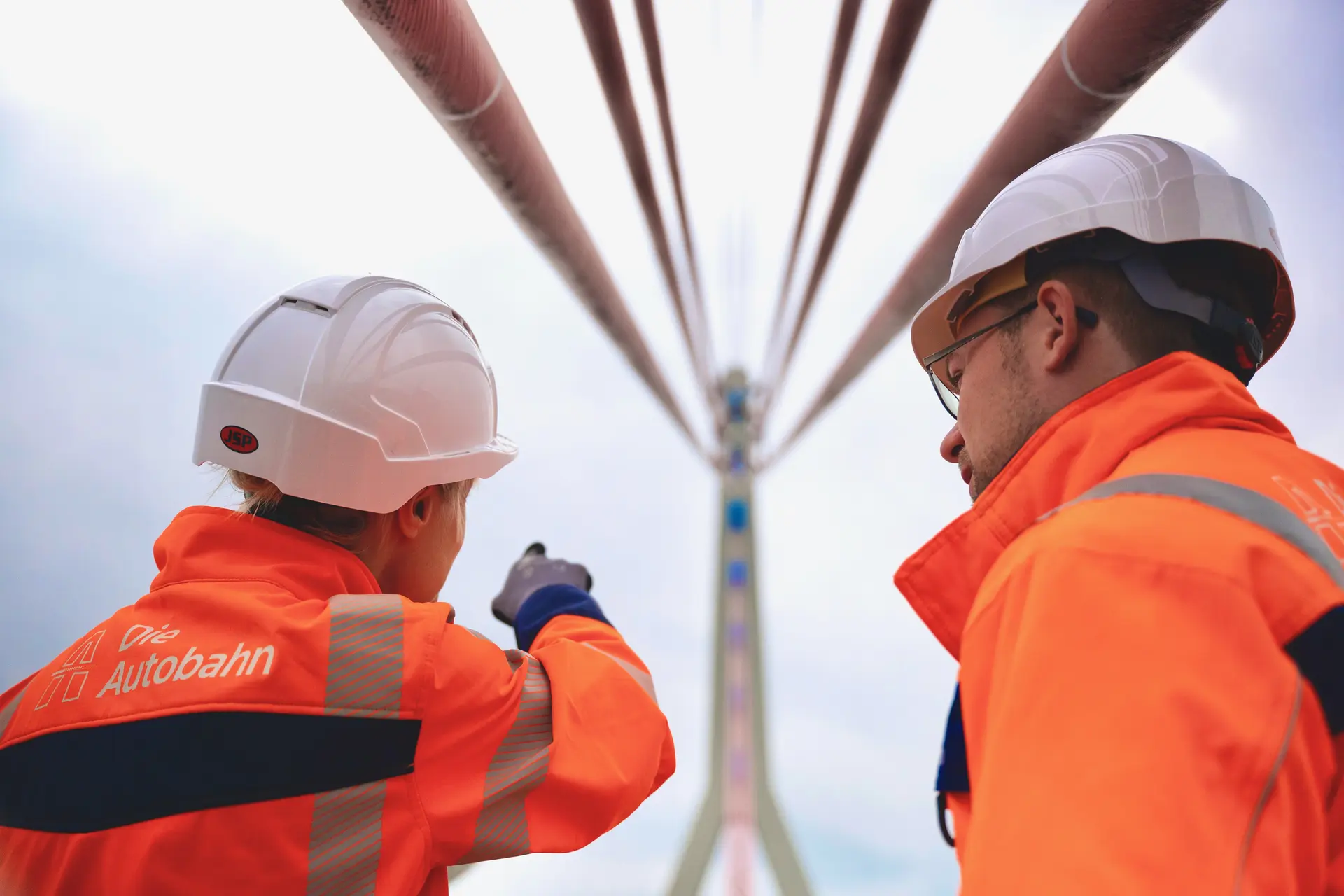 Zwei Brückenbauingenieure zeigen auf eine Brücke