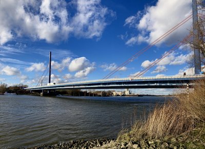 Blick auf die Norderelbbrücke Richtung Hamburg bei blauem, wolkenbehangenem Himmel.